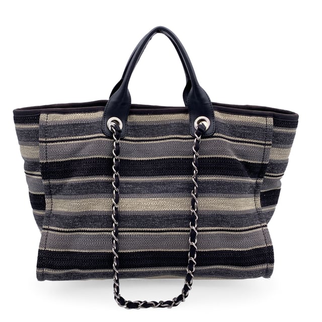 VINTAGE, RRP AS NEW
Beautiful Chanel 'Deauville' tote, crafted in black, grey and beige striped canvas with a white 'Chanel CC31, Rue cambon - Paris' logo. Period/Era: 2018/2019. Double black eather top handles and silver metal and interwoven leather shoulder straps. Magnetic button closure on top. The interior is in beige canvas lining. 2 side zip pockets inside. Leather strap with hook inside. 'CHANEL - made in Italy' tag inside. ity hologram tag inside Condition Rating: B - VERY GOOD CONDITIONCondition Details: Gently used. Some normal wear of use on bottom corners. Some darkness, small stains and normal wear of use on the internal lining. The fabric of the upper border is slightly discolored. Please, check carefully the photos or ask if you have any doubts. Measurements (cm):Depth: 20.3Height: 25.4Length: 43.2Other Details: Dustbag? NoKeys? NoBox? NoMeasurments:  width: 203 mm length: 432 mm height: 254 mm