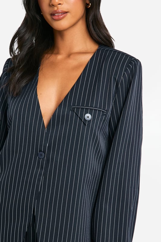Petite Collarless Pinstripe Tailored Blazer Collarless design for a modern twist on classic tailoring
Pinstripe pattern adds a sophisticated touch
Tailored fit flatters the petite frame
Functional chest pocket for added utility
Versatile piece suitable for both work and casual settings
This petite collarless pinstripe blazer from Boohoo is a versatile addition to any wardrobe. The tailored fit is designed to flatter smaller frames, while the collarless neckline offers a contemporary twist on traditional suiting. Style it as seen on the model with matching shorts for a coordinated look that's perfect for daytime events. For a more casual vibe, pair it with your favourite jeans and trainers. The blazer's adaptability makes it ideal for various occasions, from family gatherings to casual office days. Layer it over a crisp white tee or a silky camisole to switch up your look. The pinstripe pattern adds a touch of sophistication, making this blazer a go-to piece for those wanting to make a stylish statement without compromising on comfort.