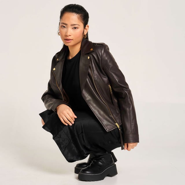 Barneys Originals real leather asymmetric biker jacket in a rich chocolate brown, featuring gold trims that beautifully complement the color. Crafted from soft, luxurious leather for a timeless and elegant finish.