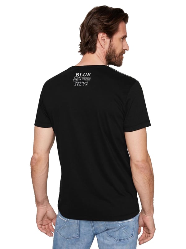 Dieses Herren-T-Shirt kombiniert modernes Design mit sportlichen Akzenten. Die normale Passform und der Rundhalsausschnitt mit Rippblende sorgen für einen klassischen Look, während ein gestreiftes Necktape im Inneren einen Hauch von Raffinesse hinzufügt. Kontrastnähte an den Schultern setzen dynamische Akzente und betonen die maskuline Silhouette. Der Front-Print mit Rubber-Details verleiht dem Shirt einen coolen, strukturierten Look. Ein kleiner Logo-Print auf der Rückseite und ein Label-Patch am linken Ärmel runden das Design ab. Das weiche Material bietet höchsten Tragekomfort, ideal für jeden Tag. Ein perfektes Shirt für den stilbewussten Mann, der Wert auf Details legt. Ob lässig oder sportlich, dieses T-Shirt ist ein echter Hingucker.