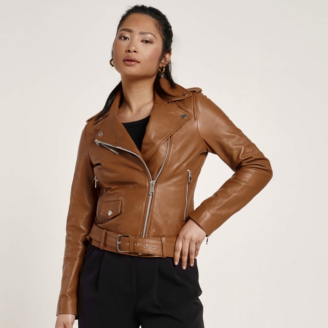 Introducing the Barneys Originals Tan Leather Biker Jacket – featuring an asymmetric design and a fixed belt, ensuring you never have to worry about losing it. Accentuated with silver trims, this jacket perfectly blends style and practicality.