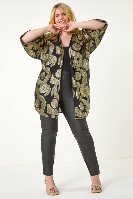 Curve Floral Foil Print Kimono from Roman. Be the star of the show at your next event with our glamorous Curve foil kimono. The woven fabric is adorned with floral foil print for a sparkling finish, perfect for special occasions. The classy edge-to-edge opening and 3/4 length sleeves add a sophisticated touch, while this kimono finishes around knee-length. Pair this kimono with wide-leg trousers and heeled boots for a stylish outfit that will turn heads wherever you go!