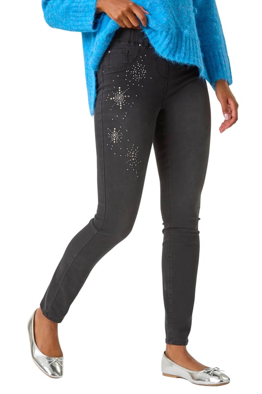 Trim Detail Jegging from Roman. Revamp your Autumn/Winter wardrobe with these embellished trim detail jeggings. These pull-on jeggings in a stretch denim fabric are designed with hotfix and stud details for a touch of sparkle and style. The unique embellishments elevate these jeggings from basic to fabulous. Perfect for a casual yet chic look, pair them with your favourite knitwear and trainers for a trendy and comfortable outfit!