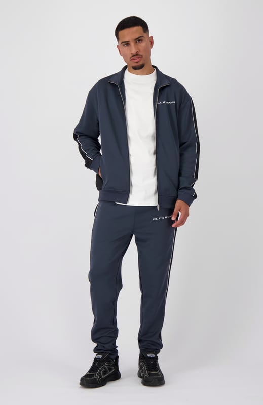 100 % Polyester Hoher Kragen mit durchgehendem Reißverschluss Schwarzes BNNS-Logo auf der Brust Zwei Reißverschluss-Fronttaschen Mit Streifen an den Ärmeln Kombinierbar mit PANEL-V1 TRACKPANTS 