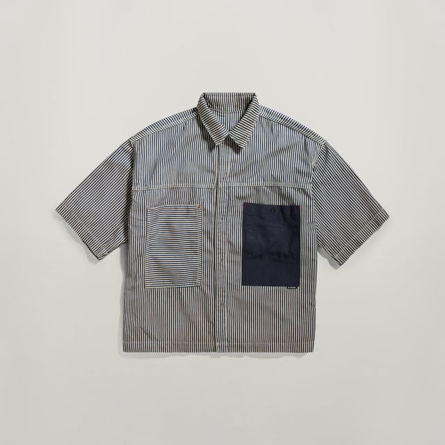 G-Star RAW Unisex Premium E Double Shirt Flat shirt. Short sleeves, double layer popping out. Visible chest pocket- smaller pocket inside, opposite site hidden inner pocket- snap button. Straight hem, double layer popping out. Loop at the upper back. Button closure. Button closure. This lightweight 6 oz fabric features a unique hickory stripe pattern. The blue yarns are dyed in indigo in the warp by using a rope dye technique. Rope dyeing consists of twisting the yarns into a rope that is then quickly dipped into indigo baths. The short dyeing time does not allow the indigo to fully penetrate the fibers and allows for a faded effect. Weight 6 oz woven, striped design. LOOSE