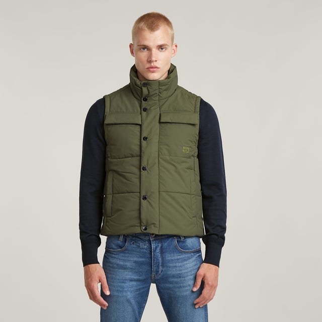Raised collar. Sleeveless. Straight hem. Flap pockets at the chest, side pockets- hidden snap button closure. Inner pocket and hanger loop. Concealed zipper closure, snap buttons. Zip & snap closure. Densely woven fabric, enriched with a PFC free water repellent finish. Vest Foundation is padded and stitched through horizontally. Pockets are created at the chest as well as the sides. The zipper closure is covered by a wind blocker with snap buttons. Inside, an additional pocket is created to complete this sleeveless padded jacket. Densely woven. Compact woven. Coated with a high performance water repellent finish for optimal functionality.