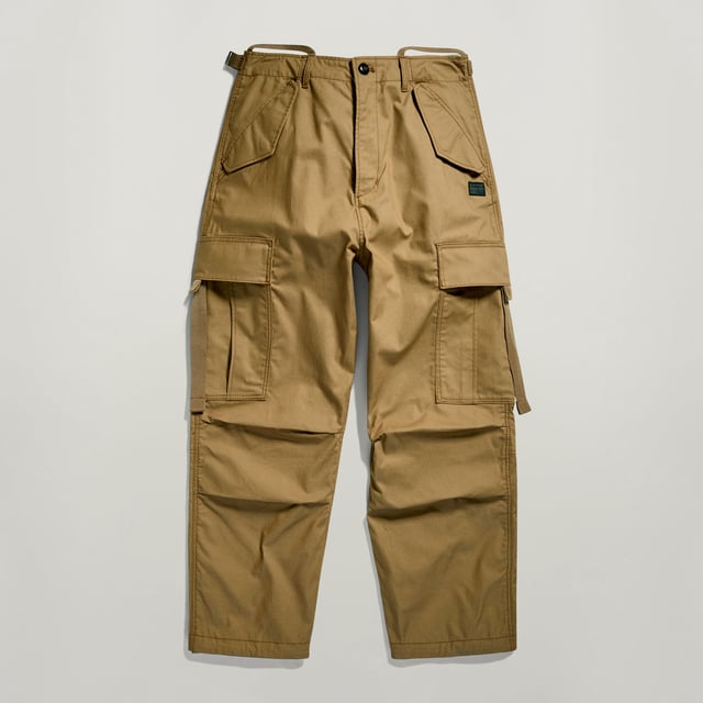 Flap pockets at the waist and back- hidden snap button. Cargo pockets at the thigh- hidden snap closure. Adjustable leg hem- Integrated tape. Zip & button closure. High waist. Cargo pants Drawcord show a straight fit with a shortened length. The straps at the back allow for a tighter waist. The pleats at the knee add more shape. The cargo pockets show an additional pull strap. 70% Cotton, 30% Cotton (Recycled). Canvas woven. Peach finish, soft touch. Straight