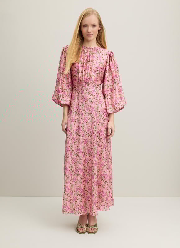 A beautiful new dress in our Royal Ascot collection, the Lois is pretty in pink with a reimagition of a French mid 19th century print. Crafted from a slinky viscose-silk blend in pink with a squiggle jacquard and a neon garden print, it has a round neck with pleating detail, puff shoulders, voluminous balloon sleeves and a long, floaty cut falling to a midi length. Wear it with heels and a hat to cheer on the winners.