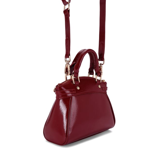 This Carvela Mini Valentina Tote bag features a wine red exterior in a trapeze style. There are two buckled straps across each side of the bag and branded gold tone hardware across the bag. Dimensions: 19cm (H), 22cm (L), 10cm (D). Strap length: 111cm.