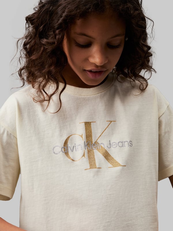 Introducing the Girls Glitter Monogram Boxy T-Shirt in Ivory by Calvin Klein Jeans, a quintessential piece for AW2024. Luxuriously tailored for the discerning young lady, this t-shirt blends elegance with a dash of playfulness. Key features include: **Chic Monogram Design**: Embellished with glittering Calvin Klein monogram for a touch of glamour. **Premium Quality Fabric**: Crafted from the finest materials for unmatched comfort and durability. **Versatile Ivory Shade**: A timeless hue that complements any outfit effortlessly. Elevate her wardrobe with this exquisite garment today!