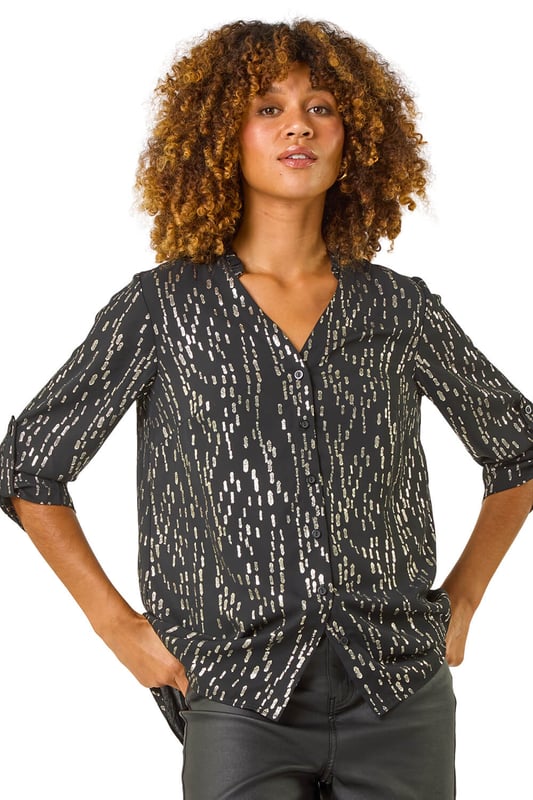 Dotted Foil Blouse from Roman. Sparkle and shine in this stunning dotted foil blouse, perfect for the Autumn/Winter season. The V-Neckline and long sleeves with cuff detail add a touch of elegance, while the mini frill detail around the neckline brings a fun element to this blouse. The foiled fabric gives a glamorous twist to the classic blouse style. Pair it with jeans and heeled boots for a chic and stylish look that will turn heads wherever you go!