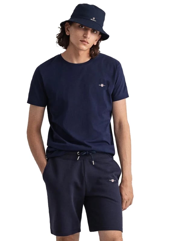 Gant introduces a mens t-shirt and shorts set with a small-scale embroidered shield graphic on the chest. Made of soft cotton and featuring a ribbed neckline, this tee showcases the iconic GANT logo. Crafted for everyday wear, the regular-fit tee is both comfortable and sustainable with Better Cotton. The included sweat shorts, also made of soft cotton blend, feature a ribbed waistband, three pockets, and a drawstring waist. The shorts are adorned with a small-scale embroidered shield graphic.