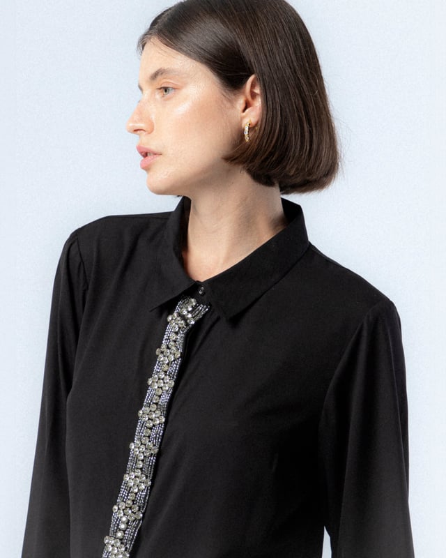 Atrévete con la camisa negra de pedrería Lucía. Con el detalle de las pedrería en el centro de la prenda, la camisa Lucía se convierte en tu mayor aliada para looks de noche este invierno.
 
 
 
 Camisa con cuello solapa.
 
 Detalle de pedrería plata en tapete.
 
 Manga larga acabada con puño.
 
 Forro de satén por separado.