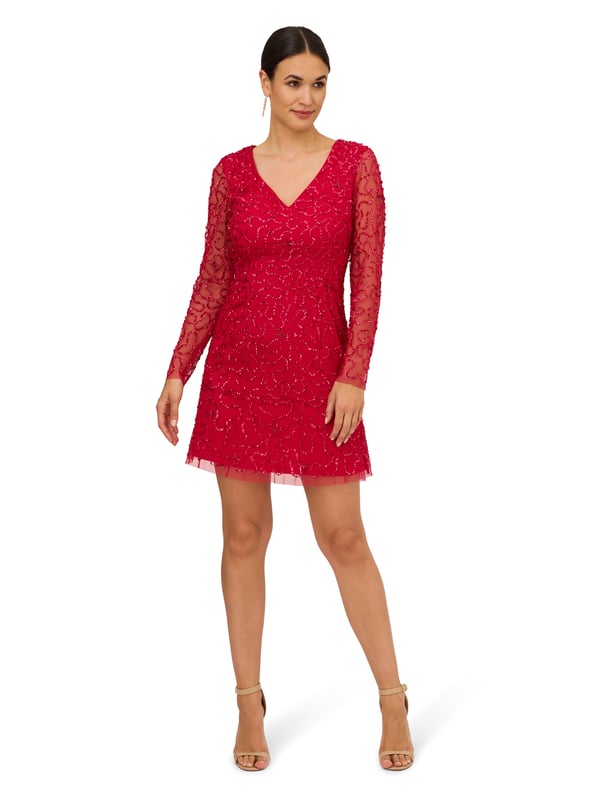 Ring in the evening with sparkle to spare in this playful sequin dress. This cocktail dress features a v-neckline, sheer long sleeves, and a soft skirt. Fully lined through the body, this long sleeve dress has a mesh overlay with swirls of sequin beading that is interspersed with clusters of tubed beading. A zipper back closure completes this beaded dress. Style this semi-formal dress with nude heels and a satin clutch to complete the look for a dressy night out or wedding guest duty.