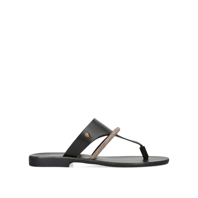 The KGL Strand is a black leather toe post sandal. There is a smaller, crystal embellished strap across the foot. The antiqued brass Eagle head sits on the outer side.