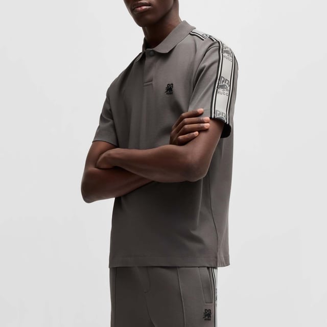 Mens Hugo X RB Branded Tape Polo Shirt in grey.- Polo collar.- One button placket.- Short sleeves.- Branded tape on the sleeves and a chest logo.- Relaxed fit.- Ref: 50530101069