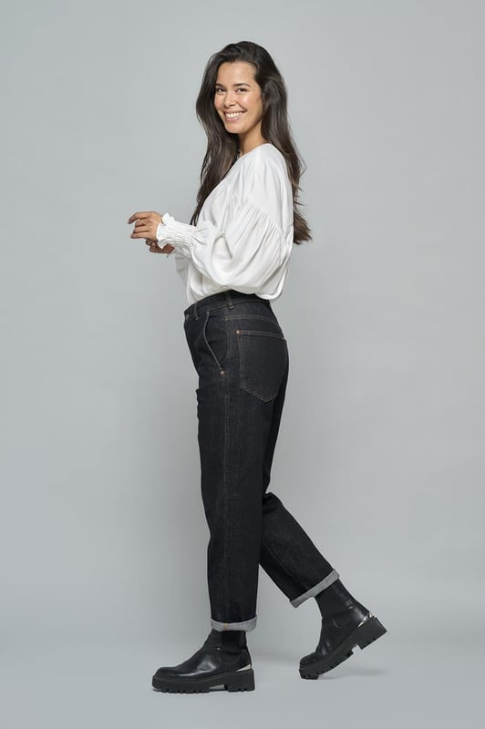 De mom-fit jeans van Caroline Tensen zijn perfect voor dit seizoen. Deze comfortabele zwarte jeans heeft een rechte pasvorm, een hoge taille en enkellange broekspijpen, en biedt dankzij de fijne stretch een uitstekende pasvorm. De stevige stretchdenim sluit mooi aan en accentueert je vrouwelijke silhouet. De jeans is afgewerkt met bruine stiksels en heeft een stoere uitstraling door de omgeslagen broekspijpen. Voor extra functionaliteit zijn er schuine steekzakken aan de voorkant en opgestikte zakken aan de achterkant. Voor een complete look kun je de jeans combineren met de bijpassende zwarte Rana denim blouse voor een unieke jumpsuit-look..!