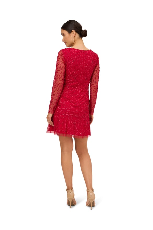 Ring in the evening with sparkle to spare in this playful sequin dress. This cocktail dress features a v-neckline, sheer long sleeves, and a soft skirt. Fully lined through the body, this long sleeve dress has a mesh overlay with swirls of sequin beading that is interspersed with clusters of tubed beading. A zipper back closure completes this beaded dress. Style this semi-formal dress with nude heels and a satin clutch to complete the look for a dressy night out or wedding guest duty.