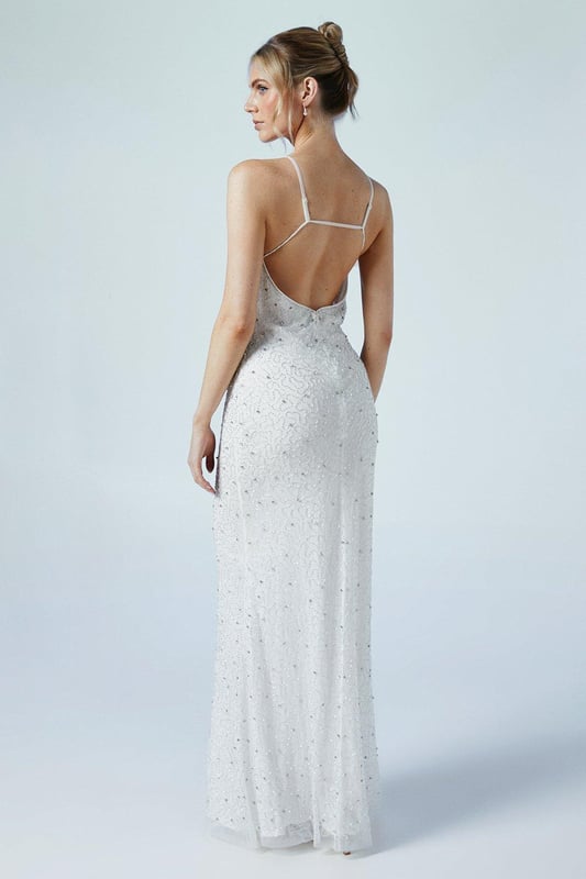 Stunning V-neck design with delicate strappy details
        Exquisite all-over beaded embellishment for a dazzling effect
        Figure-flattering jersey fabric that drapes beautifully
        Floor-length silhouette for a truly elegant bridal look
        Low back design adds a touch of allure
    
    Make a breathtaking entrance on your special day with this enchanting wedding dress from Coast. The alluring V-neckline and strappy details create a graceful silhouette, while the all-over beaded embellishment catches the light with every movement, ensuring you shine as you walk down the aisle. The jersey fabric offers both comfort and elegance, hugging your curves in all the right places. Perfect for the modern bride who desires a blend of sophistication and romance, this gown is ideal for both traditional church ceremonies and stylish outdoor celebrations. Pair with delicate drop earrings and a simple veil to complete your bridal ensemble, or style with statement heels and an elegant updo for a contemporary twist on classic bridal attire.