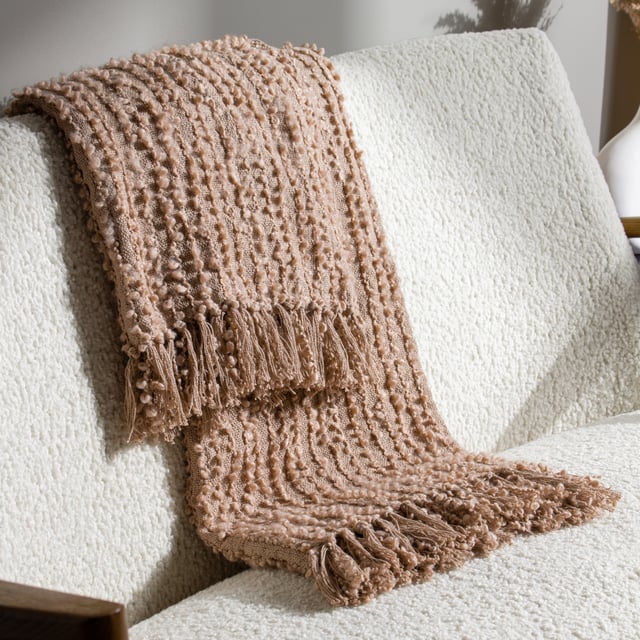 Add instant style and texture to any space with the Arvo throw. This woven design is adorned with elegant strands of vertical boucle yarn, which slide gracefully down the piece, until they meet the textural fringing at both ends. It comes in a range of muted, chic tones, which are inspired by modern neutrals and fashion fabrics. A simple, but polished throw to drape on your sofa or bed to add instant style and texture to your home.