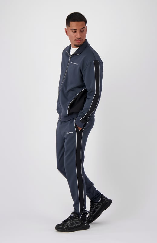 100 % Polyester Hoher Kragen mit durchgehendem Reißverschluss Schwarzes BNNS-Logo auf der Brust Zwei Reißverschluss-Fronttaschen Mit Streifen an den Ärmeln Kombinierbar mit PANEL-V1 TRACKPANTS 