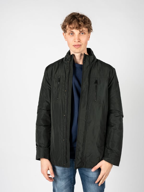 El estilo sencillo es la combinación perfecta de clásico y moderno, lo que hace que esta chaqueta se adapte perfectamente a diversos estilos, desde casual hasta más elegantes, manteniendo su carácter único y minimalista.

En el cuello alto, que añade elegancia a la chaqueta y proporciona protección adicional contra el viento, puedes confiar en los días más fríos, y su diseño sutil hace que la chaqueta gane en universalidad y sea ideal para cualquier ocasión.

Con una capucha oculta en el cuello, este elemento práctico permite una rápida adaptación a los cambios del tiempo, ofreciendo protección contra la lluvia cuando más lo necesitas, sin renunciar a la estética.

Cerrada con una cremallera logotipada y botones a presión, la chaqueta no solo proporciona un cierre seguro y cómodo, sino que también constituye un acento elegante, que subraya sutilmente su carácter de marca.

En el frente, cuatro bolsillos con cremallera ofrecen no solo mucho espacio para los elementos esenciales, sino también garantizan la seguridad de los objetos almacenados, permitiéndote disfrutar de plena funcionalidad y comodidad diaria.

Ajustable con cordones en la cintura, la chaqueta permite un ajuste perfecto al cuerpo, lo que no solo resalta su aspecto moderno, sino que también proporciona confort adicional, adaptándose a tus necesidades individuales.

En la manga izquierda, un detalle de la marca constituye una referencia sutil, pero clara, a la marca, añadiendo prestigio a la chaqueta y destacando su exclusividad, lo que seguramente atraerá la atención de aquellos que valoran los detalles de marca.

Hecha de un tejido de alta calidad, transpirable y resistente al agua, la chaqueta no solo proporciona comodidad térmica y protección contra la humedad, sino que también cuida la adecuada circulación del aire, lo que la hace una opción ideal para diversas condiciones climáticas.