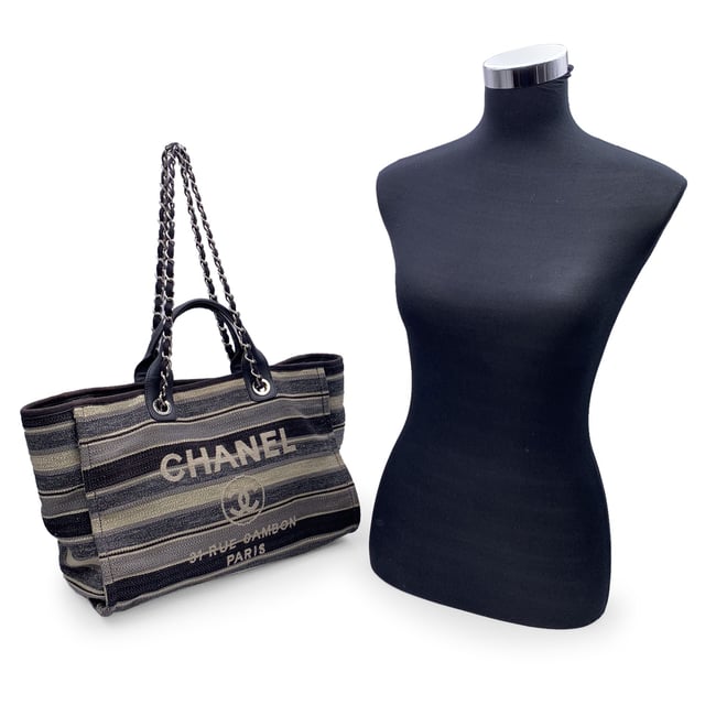 VINTAGE, RRP AS NEW
Beautiful Chanel 'Deauville' tote, crafted in black, grey and beige striped canvas with a white 'Chanel CC31, Rue cambon - Paris' logo. Period/Era: 2018/2019. Double black eather top handles and silver metal and interwoven leather shoulder straps. Magnetic button closure on top. The interior is in beige canvas lining. 2 side zip pockets inside. Leather strap with hook inside. 'CHANEL - made in Italy' tag inside. ity hologram tag inside Condition Rating: B - VERY GOOD CONDITIONCondition Details: Gently used. Some normal wear of use on bottom corners. Some darkness, small stains and normal wear of use on the internal lining. The fabric of the upper border is slightly discolored. Please, check carefully the photos or ask if you have any doubts. Measurements (cm):Depth: 20.3Height: 25.4Length: 43.2Other Details: Dustbag? NoKeys? NoBox? NoMeasurments:  width: 203 mm length: 432 mm height: 254 mm