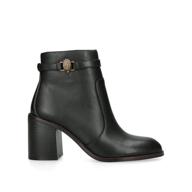 The Kurt Geiger Shoreditch Block Ankle boot is crafted from a black leather. The ankle feature an antiqued brass eagle head with antiqued brass zipper pull on the opposite side. Heel height: 8cm.