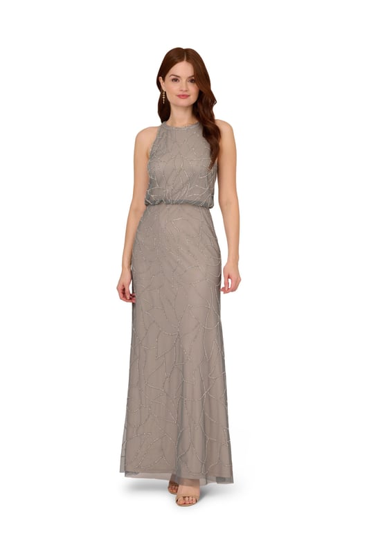 Timelessly sparkle at your next formal event in this blouson gown. This formal dress features a sleeveless blouson bodice, a halter neckline, and a mermaid skirt. Fully lined, this evening gown is designed with mesh knit fabric that is fully embellished with sequin and beaded floral deco patterns. A hidden zipper closure at the centre back completes this sleeveless gown. Paired with nude heels and simple accessories, this beaded dress is ideal for black-tie events or bridal parties.