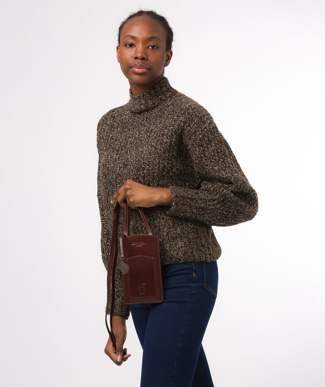 The 'Siren' from Conkca London is handcrafted from genuine leather for a beautiful finish. This open-top phone bag is the perfect way to keep your phone on your person whilst keeping your hands free. The interior is lined with natural and untreated 100% cotton. Includes a cotton-lined slip pouch on the front and two card slots on the rear, ideal for maintaining an organised bag. Comes with an adjustable leather strap with a drop length of 70cm, alongside gold metal fittings. Adorned with the iconic Conkca logo and charm.