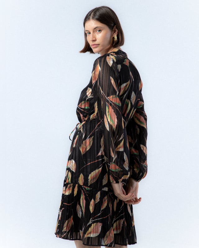 El vestido cruzado Nicola, con su sofisticado estampado de hojas en tonos cálidos sobre fondo oscuro, te hará sentir la esencia del otoño. Su diseño cruzado favorecedor y su estilo elegante lo convierten en la prenda perfecta para realzar tu feminidad en cualquier ocasión especial.
 
 
 
 Vestido corto con cuello pico. 
 
 Manga larga con puño elástico. 
 
 Cinturón de cordón con terminación de abalorios. 
 
 Bajo en volante tableado. 
 
 Tejido con textura de rayas satinadas. 
 
 Estampado de hojas.