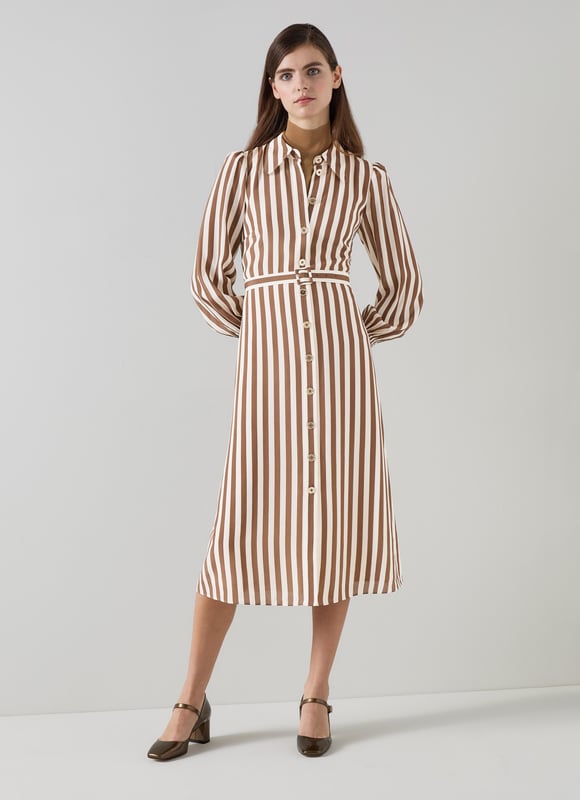 Imagine a breezy afternoon stroll wearing the Emelia candy stripe shirt dress in chocolate and birch. This stylish piece in chocolate and birch silk boasts a classic collar, full length sleeves, and a sophisticated woven stripe design, perfect for smart casual outings. Pair it with elegant flats for a daytime look or enhance it with heels for an evening out.