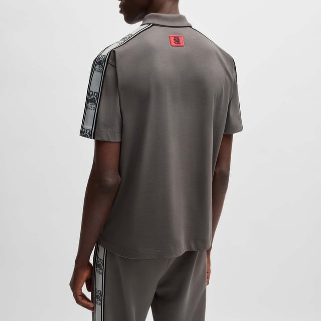 Mens Hugo X RB Branded Tape Polo Shirt in grey.- Polo collar.- One button placket.- Short sleeves.- Branded tape on the sleeves and a chest logo.- Relaxed fit.- Ref: 50530101069