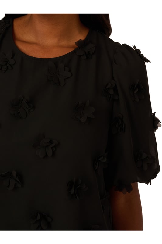 Add a fun dimensional moment to your outfit with this cute short sleeve top dotted with fluttery chiffon flower appliques. Balloon sleeves hit just above the elbow to complete the sweet, romantic feel of this blouse. A keyhole button closure at the back finishes the crew neck collar. Perfect for work and weekend style, you will love the way this charming top dresses up any look.