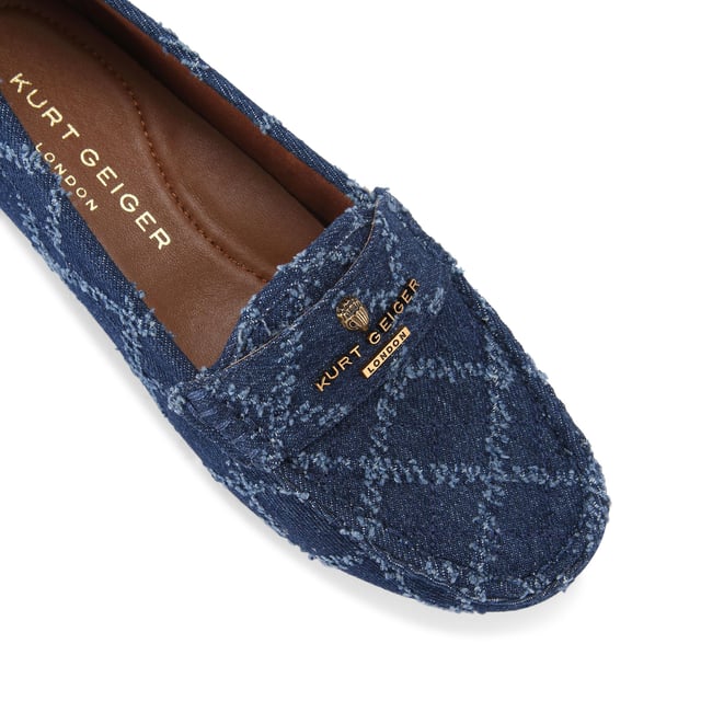 The Kurt Geiger Greenwich Moccasin slip-on loafer features a blue denim upper with frayed diamond quilting design. There is antiqued brass branding on the front alongside micro eagle head.