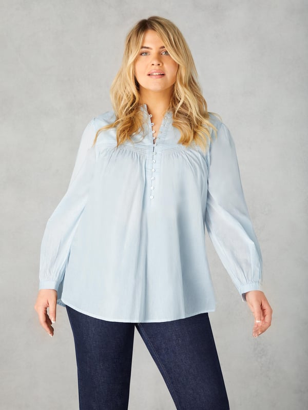 In classic blue, this blouse is cut from the softest of cottons. With a nehru collar, it has a button-up front placket with pretty rouleau buttons, as well as shirring detail at the yoke. Full-length sleeves with button up cuffs create an elegant silhouette, especially when combined with its high-low hem which provides that all-important coverage.