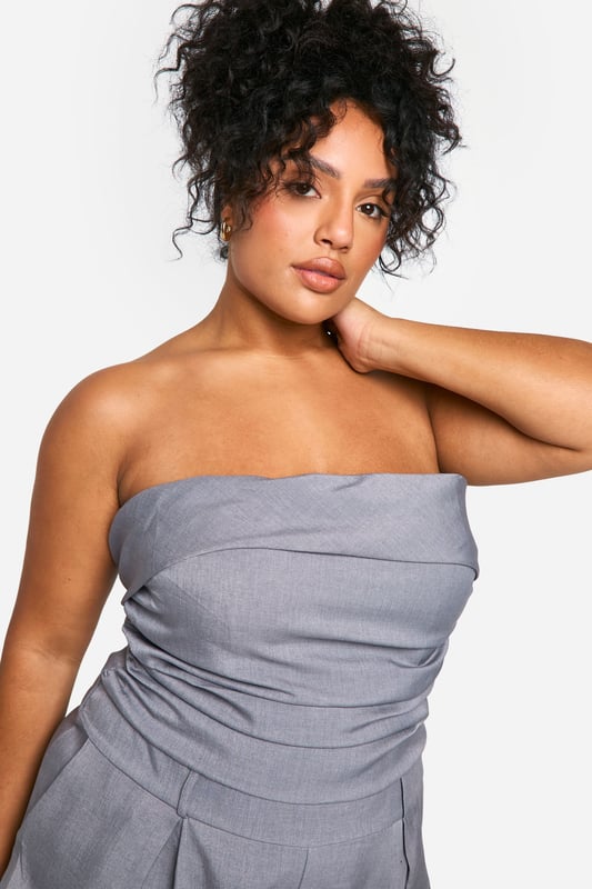 Chic bandeau neckline for a sleek, strapless look
        Flattering ruched detailing accentuates curves
        Versatile playsuit design perfect for day-to-night wear
        Comfortable elasticated waistband for a secure fit
        Practical side pockets add functionality to style
    
    Embrace effortless elegance with this stunning plus-size bandeau playsuit from Boohoo. The ruched detailing adds a touch of sophistication while flattering your curves in all the right places. Perfect for transitioning from day to night, this versatile piece can be dressed up or down with ease. For a chic daytime look, pair with flat sandals and oversized sunglasses. When the sun sets, swap your flats for strappy heels and add statement earrings to take your outfit from desk to dinner. The playsuit's comfortable fit and practical pockets make it ideal for various occasions, from casual brunches to evening cocktails. Layer with a cropped jacket for cooler evenings or rock it solo to show off its sleek silhouette. With its blend of style and comfort, this playsuit is sure to become a go-to favourite in your wardrobe.