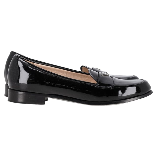 VINTAGE, RRP WIE NEU  
Die Prada Logo Plaque Loafers aus schwarzem Lackleder sind eine elegante und anspruchsvolle Schuhwahl, die zeitlosen Stil mit zeitgenössischem Luxus verbindet. Hergestellt aus hochwertigem Lackleder, verfügen diese Loafers über eine glänzende Oberfläche, die jedem Outfit einen Hauch von Glanz und Raffinesse verleiht. Die charakteristische Prada-Logo-Plakette auf der Vorderseite verleiht ein markantes, elegantes Detail und hebt die klassische Loafer-Silhouette hervor.

Prada Logo Plaque Loafers aus schwarzem Lackleder

Zustand: Sehr gut  
Abnutzungsspuren: Inklusive Box. Kleinere Abnutzungserscheinungen, leicht benutzt, aber sehr gut gepflegt. Kleine Markierung an den Sohlen & Faltenbildung, leichte Abschürfungen an den Sohlen und Fersen.  
Verpackung: Box  
Farbe: Schwarz  
Material: Leder | Lackleder  
Größe: IT | 38.5/UK5.5/US8.5/FR39.5  
Maße: Innensohlenlänge: 280  
SKU: NAPPUGBSH446784W