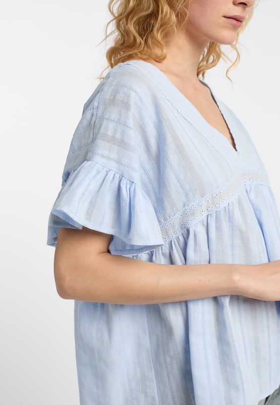 Diese leichte Baumwoll-Bluse von DreiMaster Vintage punktet mit ihrer zauberhaften Lochstickerei und dem gemusterten, fein strukturierten Baumwollstoff. Die lockerere Silhouette hat einen tiefen V-Ausschnitt auf der Vorder- und auf der Rückseite, wo er mit einem Spitzenband zusammengehalten wird. Die romantischen Rüschenärmel optimieren den femininen Boho-Look. Mit ihrer leichten Textur passt sie hervorragend zu Jeans und Röcken.  Tunika