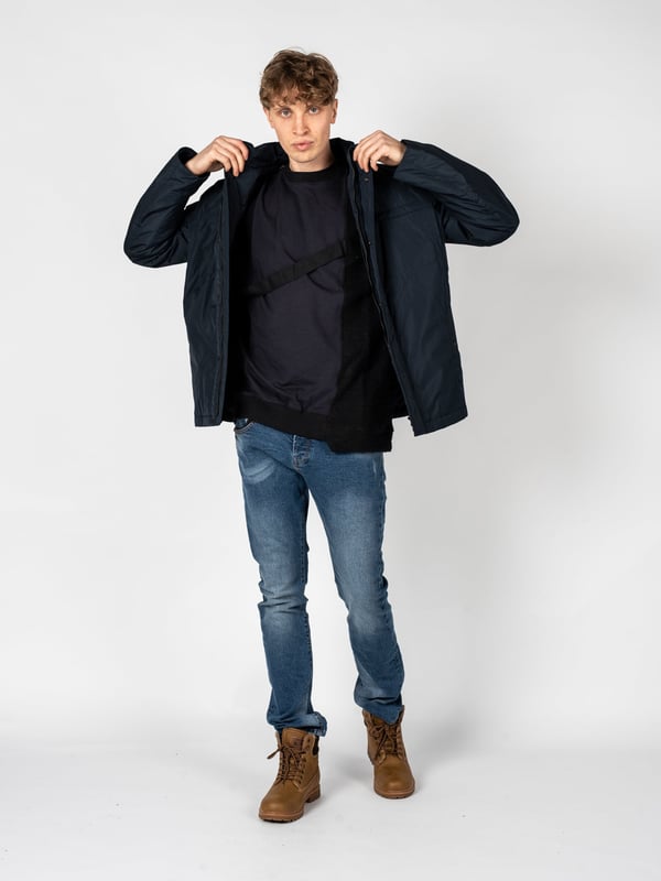 Un diseño sencillo es la solución perfecta para aquellos que valoran la clásica y el minimalismo, al mismo tiempo que desean verse estilosos y elegantes en cualquier situación.

El cuello alto añade un carácter moderno al conjunto, a la vez que ofrece protección adicional contra el viento y el frío, lo que hace que esta prenda sea una excelente elección para las condiciones meteorológicas cambiantes.

Con una capucha oculta en el cuello, puedes estar preparado para las lluvias inesperadas, y su ingenioso diseño permite que se guarde fácilmente cuando no es necesaria, manteniendo un aspecto elegante.

Se abrocha con una cremallera logotipada y botones a presión, lo que no solo añade un estilo único, sino que también proporciona protección adicional contra el frío, destacando al mismo tiempo la atención a los detalles.

En el frente, cuatro bolsillos, dos con cremallera y dos con botones a presión, ofrecen mucho espacio para guardar los artículos esenciales y su variedad permite una mejor organización.

En la manga izquierda, un detalle de la marca constituye un sutil, pero claro refuerzo del prestigio de la marca, agregando un carácter exclusivo a la prenda y distinguiéndola de las demás.

Fabricada con tela de alta calidad, transpirable y resistente al agua, lo que garantiza no solo comodidad al usarla, sino también protección contra las condiciones atmosféricas adversas, haciendo que sea una elección ideal para cualquier época del año.