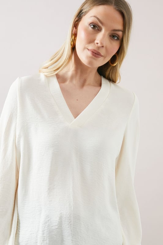 Elegant V-neckline for a flattering silhouette
        Voluminous balloon sleeves add a touch of drama
        Relaxed, over-the-head design for effortless wear
        Versatile woven fabric suitable for various occasions
        Subtle textured finish for added visual interest
    
    Embrace sophisticated comfort with this Wallis over-the-head top. The flowing silhouette and statement balloon sleeves create a look that's both relaxed and refined. Perfect for daytime engagements, this versatile piece can be styled for a range of casual events. Pair it with wide-leg trousers and sandals for a chic family lunch, or team it with your favourite jeans and trainers for a stylish weekend brunch. The V-neckline offers a feminine touch, while the textured fabric adds depth to your ensemble. For a polished daytime look, accessorise with delicate gold jewellery and a woven handbag. This top effortlessly bridges the gap between comfort and style, making it an essential addition to your wardrobe for those occasions when you want to feel put-together yet at ease.