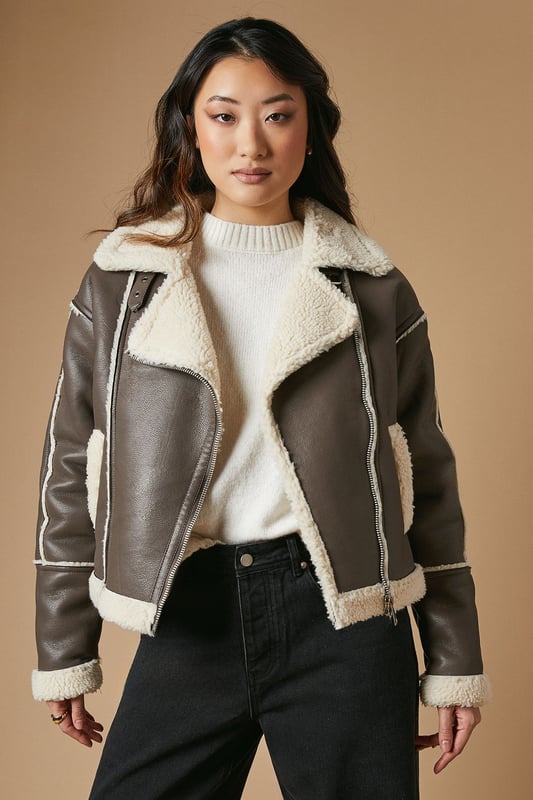 Striking contrast borg detailing for added warmth and style
        Asymmetrical zip front closure for a modern edge
        Oversized collar for a bold, fashion-forward look
        Cropped length perfect for layering
        Versatile design suitable for various casual occasions
    
    This PU borg detail collared zip jacket from Oasis is the epitome of cool-weather chic. The contrasting borg lining not only adds a cosy touch but also creates a striking visual appeal. Its asymmetrical zip closure and oversized collar lend a contemporary edge to your ensemble. The cropped silhouette is ideal for showcasing high-waisted bottoms, as demonstrated by the model pairing it with wide-leg trousers. For a casual day out, style it with your favourite jeans and trainers. Alternatively, dress it up for an evening with friends by layering it over a fitted dress and ankle boots. This jacket is a versatile piece that will quickly become a go-to in your autumn and winter wardrobe, perfect for family gatherings, weekend brunches, or casual outings where you want to make a stylish statement without compromising on comfort.