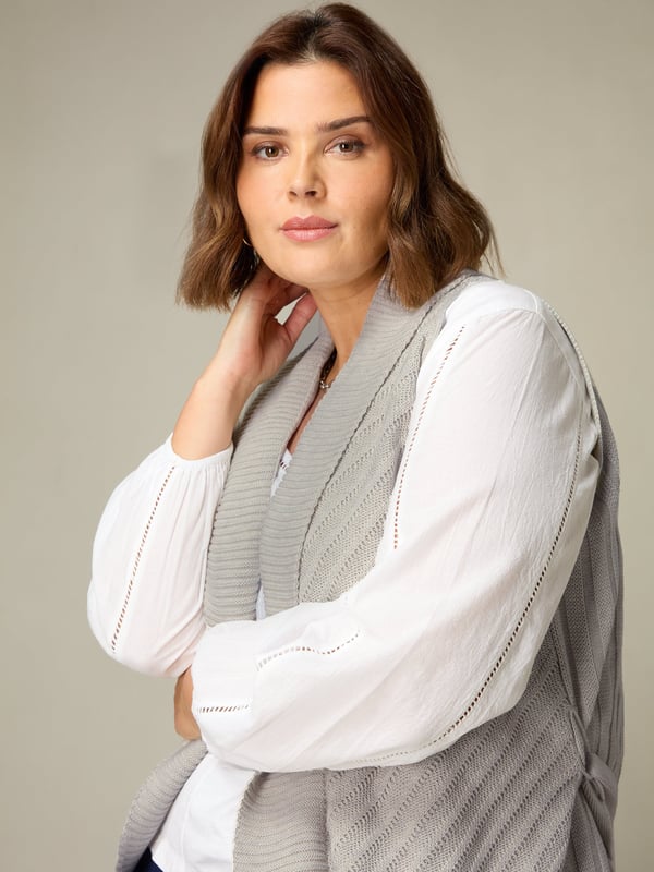 In stylish grey, this sleeveless cardigan is knitted from a soft, fine knit and has a flattering longline shape. With a shawl collar and softly draping front, its the perfect piece to layer over a T-shirt or blouse as the weather grows chillier.