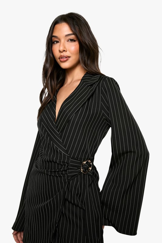 Striking pinstripe pattern for a bold, sophisticated look
        Wrap-style neckline adds a feminine touch
        Unique buckle detail at the waist for added interest
        Flared sleeves create a dramatic silhouette
        Versatile blazer dress design perfect for day-to-night transitions
    
    Make a statement in this eye-catching blazer dress from Boohoo. The pinstripe pattern adds a touch of classic sophistication, while the wrap-style neckline and buckle detail at the waist create a flattering, feminine silhouette. The flared sleeves add drama and movement to the overall look. Perfect for a night out with friends, this versatile piece can be dressed up or down. Pair it with strappy heels and statement earrings for a chic evening ensemble, or layer it over a turtleneck with ankle boots for a stylish daytime outfit. The blazer dress design offers endless styling possibilities, making it a must-have addition to your wardrobe. Whether you're heading to drinks at a trendy bar or dancing the night away at a club, this dress will ensure you stand out from the crowd.