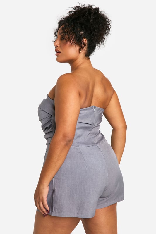 Chic bandeau neckline for a sleek, strapless look
        Flattering ruched detailing accentuates curves
        Versatile playsuit design perfect for day-to-night wear
        Comfortable elasticated waistband for a secure fit
        Practical side pockets add functionality to style
    
    Embrace effortless elegance with this stunning plus-size bandeau playsuit from Boohoo. The ruched detailing adds a touch of sophistication while flattering your curves in all the right places. Perfect for transitioning from day to night, this versatile piece can be dressed up or down with ease. For a chic daytime look, pair with flat sandals and oversized sunglasses. When the sun sets, swap your flats for strappy heels and add statement earrings to take your outfit from desk to dinner. The playsuit's comfortable fit and practical pockets make it ideal for various occasions, from casual brunches to evening cocktails. Layer with a cropped jacket for cooler evenings or rock it solo to show off its sleek silhouette. With its blend of style and comfort, this playsuit is sure to become a go-to favourite in your wardrobe.