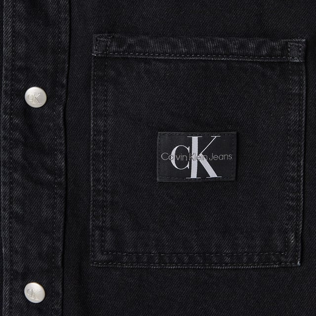 Mens Calvin Klein Logo Patch Denim Shirt in black.- Classic collar.- Front press-stud fastening.- Two chest flap pockets.- Press-stud fastening cuffs.- Faded effect.- Curved hem.- Ref: J30J3258951BY