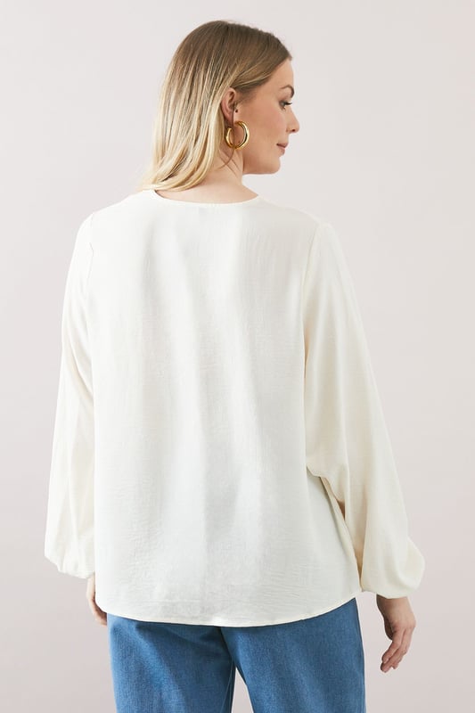 Elegant V-neckline for a flattering silhouette
        Voluminous balloon sleeves add a touch of drama
        Relaxed, over-the-head design for effortless wear
        Versatile woven fabric suitable for various occasions
        Subtle textured finish for added visual interest
    
    Embrace sophisticated comfort with this Wallis over-the-head top. The flowing silhouette and statement balloon sleeves create a look that's both relaxed and refined. Perfect for daytime engagements, this versatile piece can be styled for a range of casual events. Pair it with wide-leg trousers and sandals for a chic family lunch, or team it with your favourite jeans and trainers for a stylish weekend brunch. The V-neckline offers a feminine touch, while the textured fabric adds depth to your ensemble. For a polished daytime look, accessorise with delicate gold jewellery and a woven handbag. This top effortlessly bridges the gap between comfort and style, making it an essential addition to your wardrobe for those occasions when you want to feel put-together yet at ease.