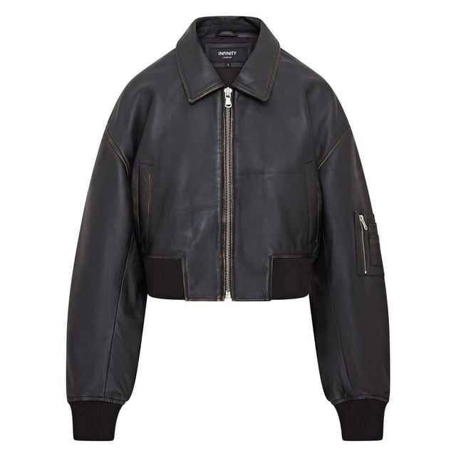 Mejora tu estilo con esta cazadora bomber de piel negra, sencilla y moderna. Diseñada para un look boyfriend relajado y oversize, esta prenda está confeccionada en suave piel de napa de oveja, con costuras y bolsillos envejecidos por expertos para un aspecto vintage. Una robusta cremallera YKK da lugar a un cuello clásico estilo camisa, mientras que el dobladillo y los puños de punto elástico garantizan un ajuste ceñido y calidez. Con dos bolsillos en la cintura y un bolsillo en la manga con cremallera, además de un lujoso forro de satén con un bolsillo interior con ribete de piel, esta cazadora combina funcionalidad con una sofisticación vanguardista. Piel de napa de oveja envejecida suave, corte oversize, cremallera YKK gruesa, dobladillo y puños de punto elástico, forro de satén con bolsillo interior con ribete de piel