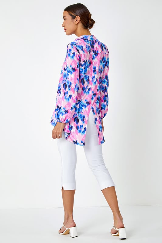 Abstract Print Dropped Hem Blouse from Roman. This sophisticated dropped hem blouse is cut from a smooth woven fabric and adorned in a colourful abstract print. It features a fully open front complete with button fastenings, full length cuffed sleeves and a smart collared neckline. A flattering dropped hem provides extra coverage at the back. Pair with cropped stretch trousers and heels for an evening out or add smart trousers and courts for work wear chic!