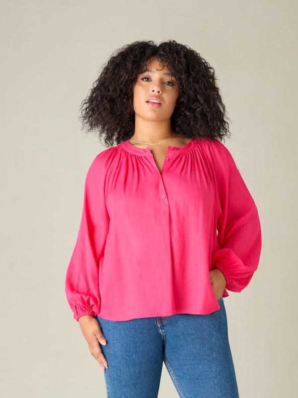 In striking pink, this blouse is cut from a soft chambray fabric thats so comfortable to wear. It has a round neckline with soft gathers, and a button-through front that creates a lengthening effect. Long raglan sleeves with elasticated cuffs add comfort and coverage, and complement its slightly swingy shape beautifully.
